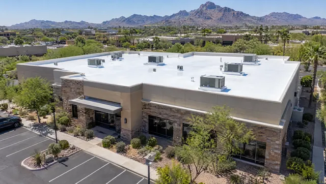 Low commercial building in Scottsdale with a large white flat foam roof and rooftop HVAC units